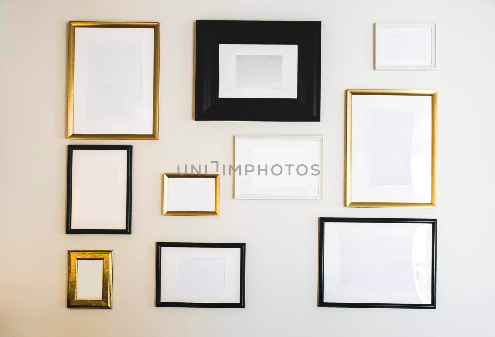 Empty gold and black photo and picture frames on white wall, mock up for your photos or text, copy space modern design luxury decoration closeup