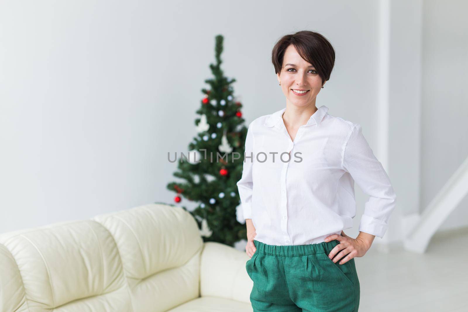 Happy young woman in living room with christmas tree. Holidays concept. by Satura86