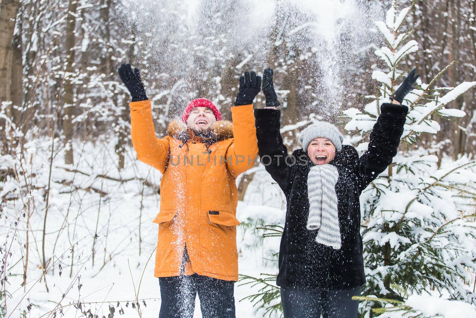 Love, season, friendship and people concept - happy young man and woman having fun and playing with snow in winter forest by Satura86