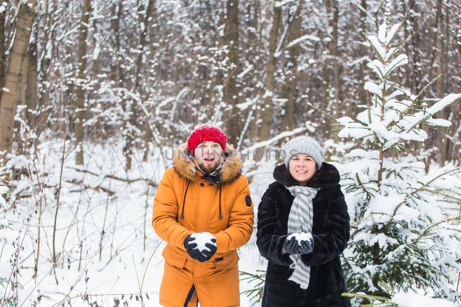 Love, season, friendship and people concept - happy young man and woman having fun and playing with snow in winter forest by Satura86