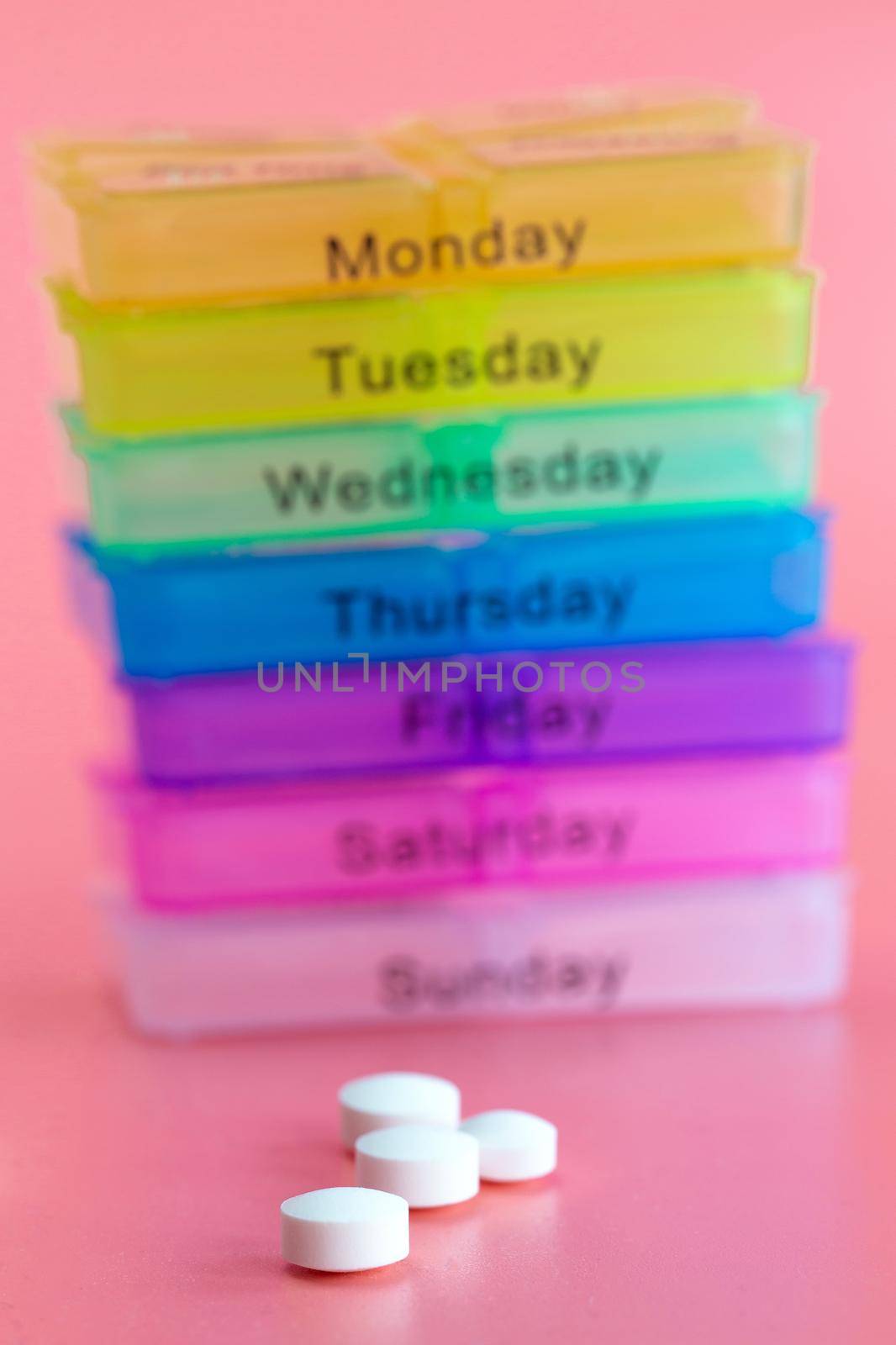 Pill box reminder, hand taking medicine daily pills in colorful box on pink background, elderly,senior,business,health,medication concept modern design close up