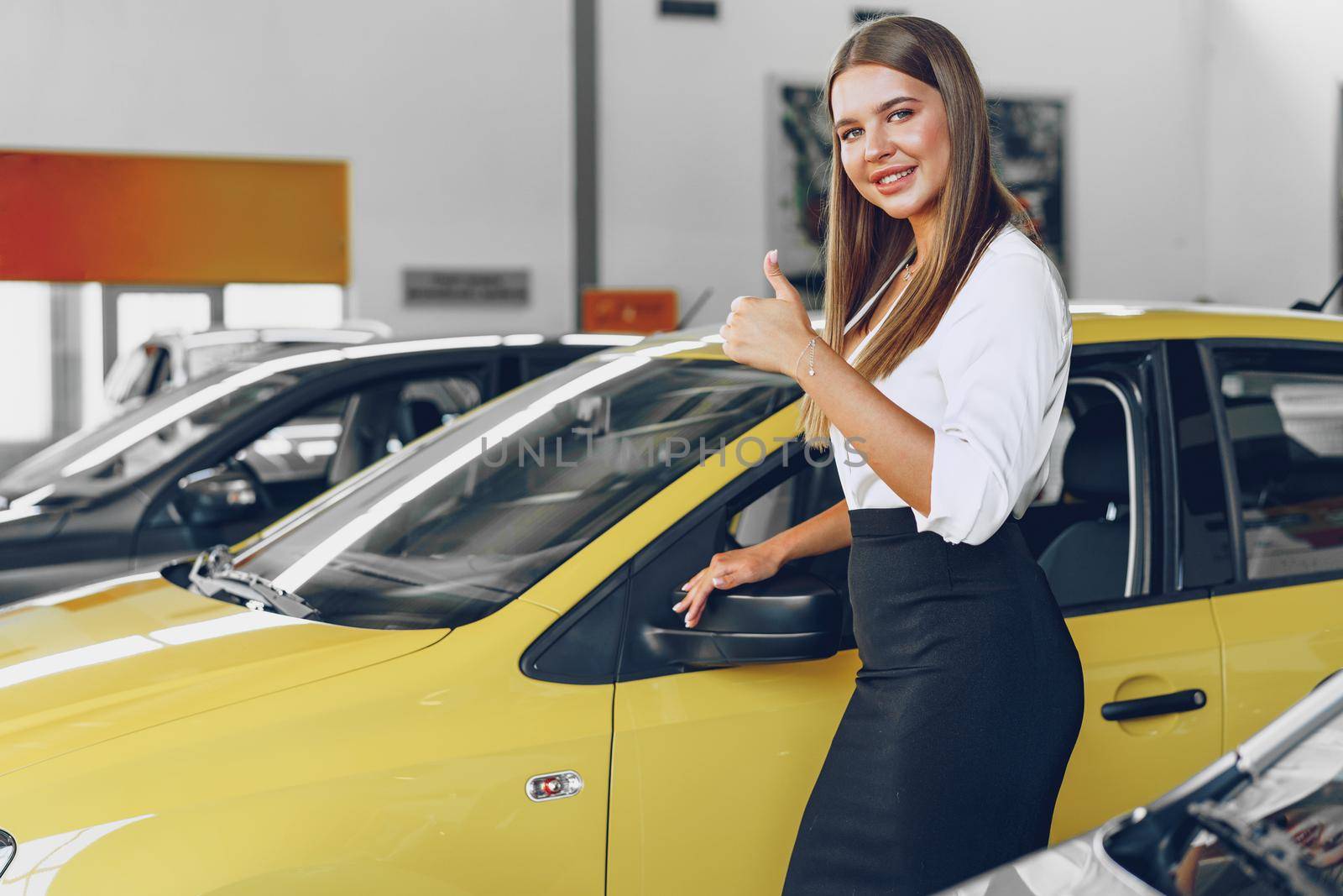 Young woman checking out a new car she is going to buy in car salon