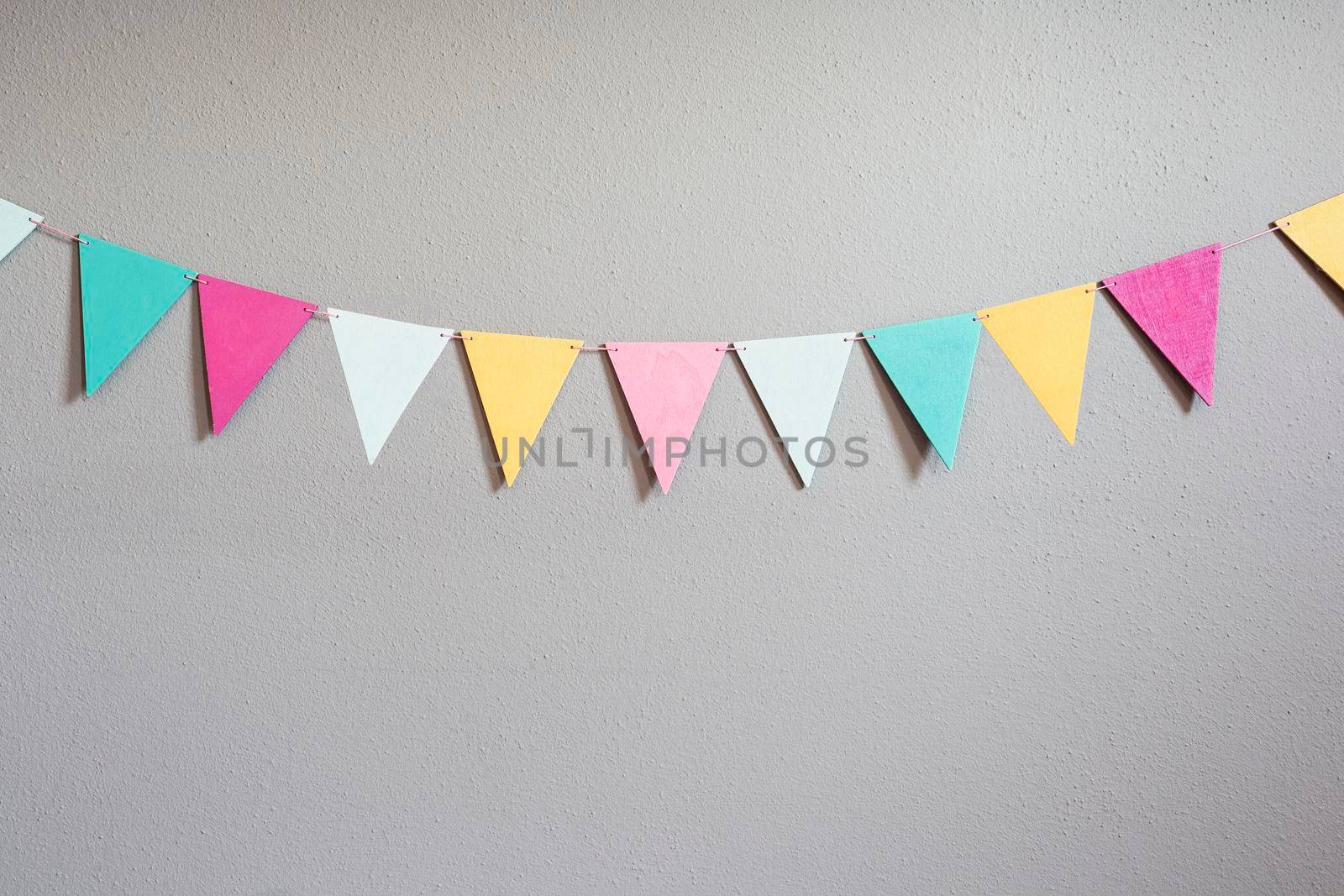 Colorful party flags over cement concrete gray wall texture background, pastel birthday colored flags with copy space Holiday concept beauty