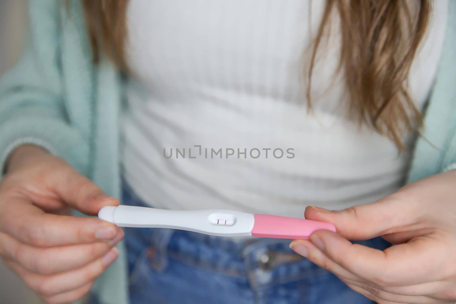 Happy young woman holding a positive pregnancy test close-up bright colors modern stylish design beautiful nature