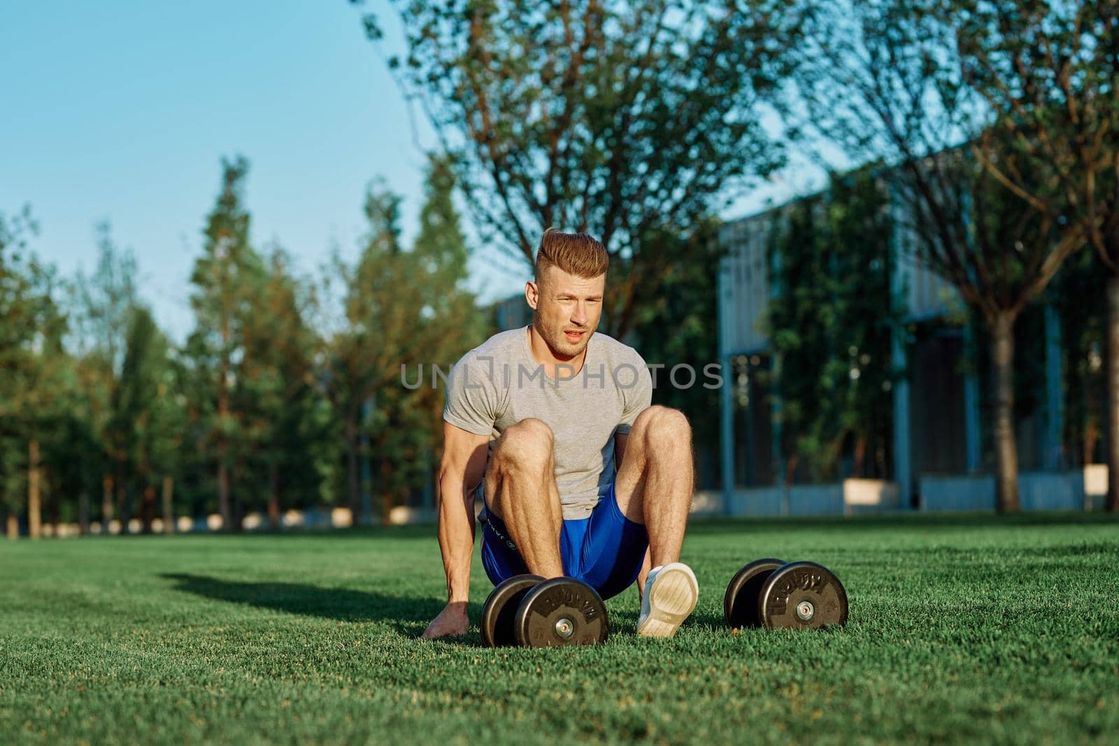 athletic man with dumbbells in the park exercise motivation by Vichizh