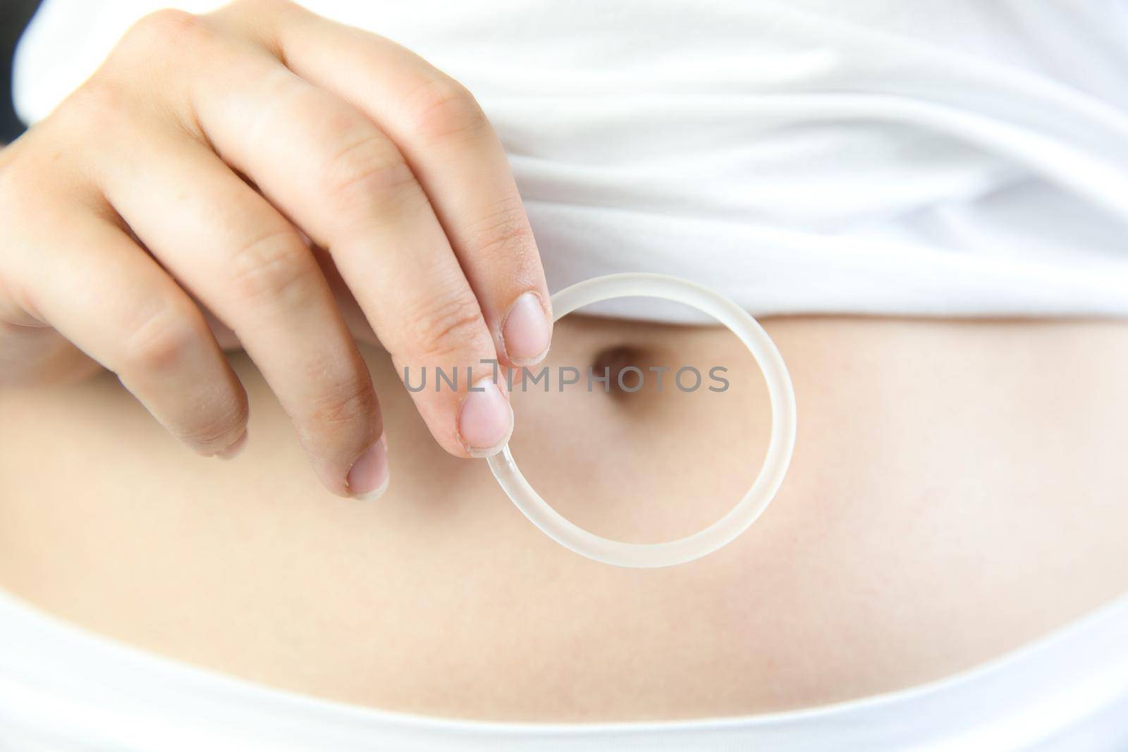 Birth control ,hormone, contraception ring in a womans hand white underwear and belly, vaginal ring for contraceptive use with copy space closeup