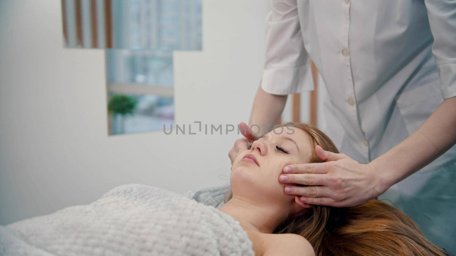 Massage - a masseuse is massaging her clients cheeks - indoor