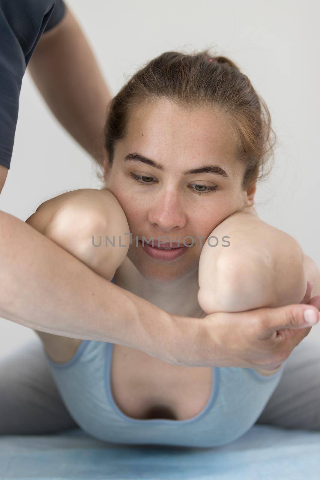 Young woman having osteopathy treatment indoors - lying in the pose with her elbows forward. Mid shot