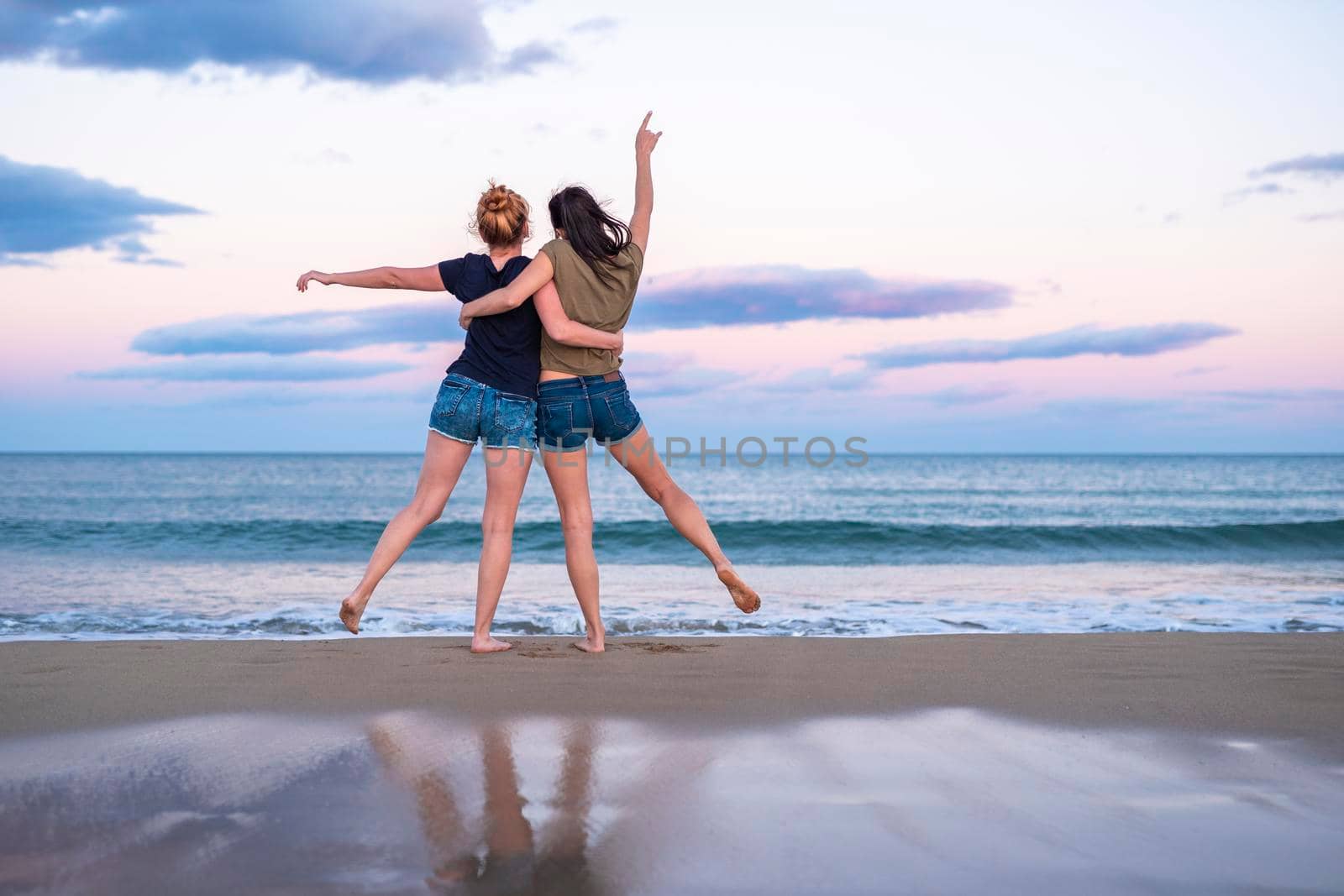 Two pretty young girls pretty best friend women having fun on their summer vacation on Mediterranean sea, mini denim shorts, amazing blonde and brunette hairs, traveling experience, happy emotions by Alexxoma