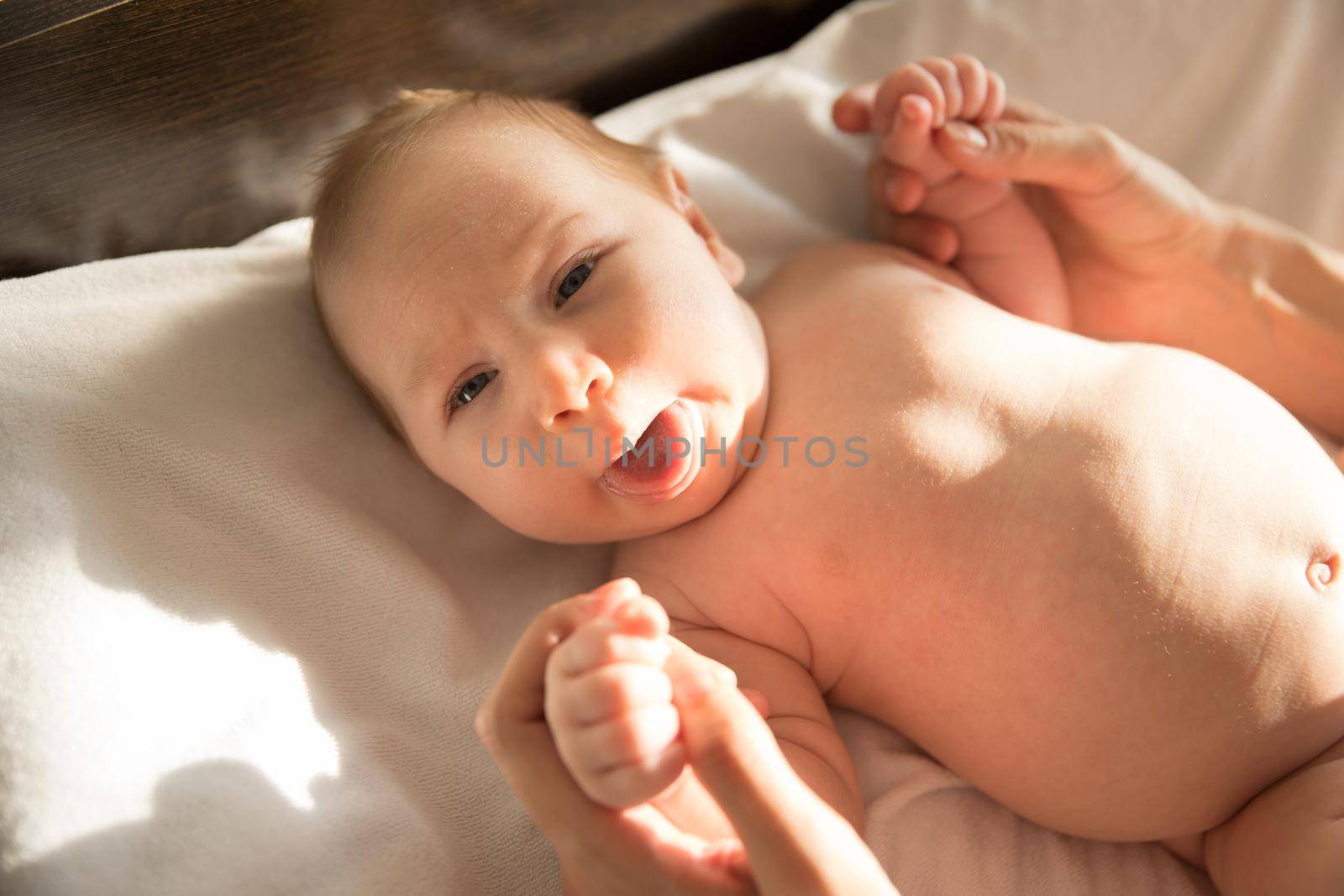 A little funny baby lying on a bed and showing his tongue. Mid shot