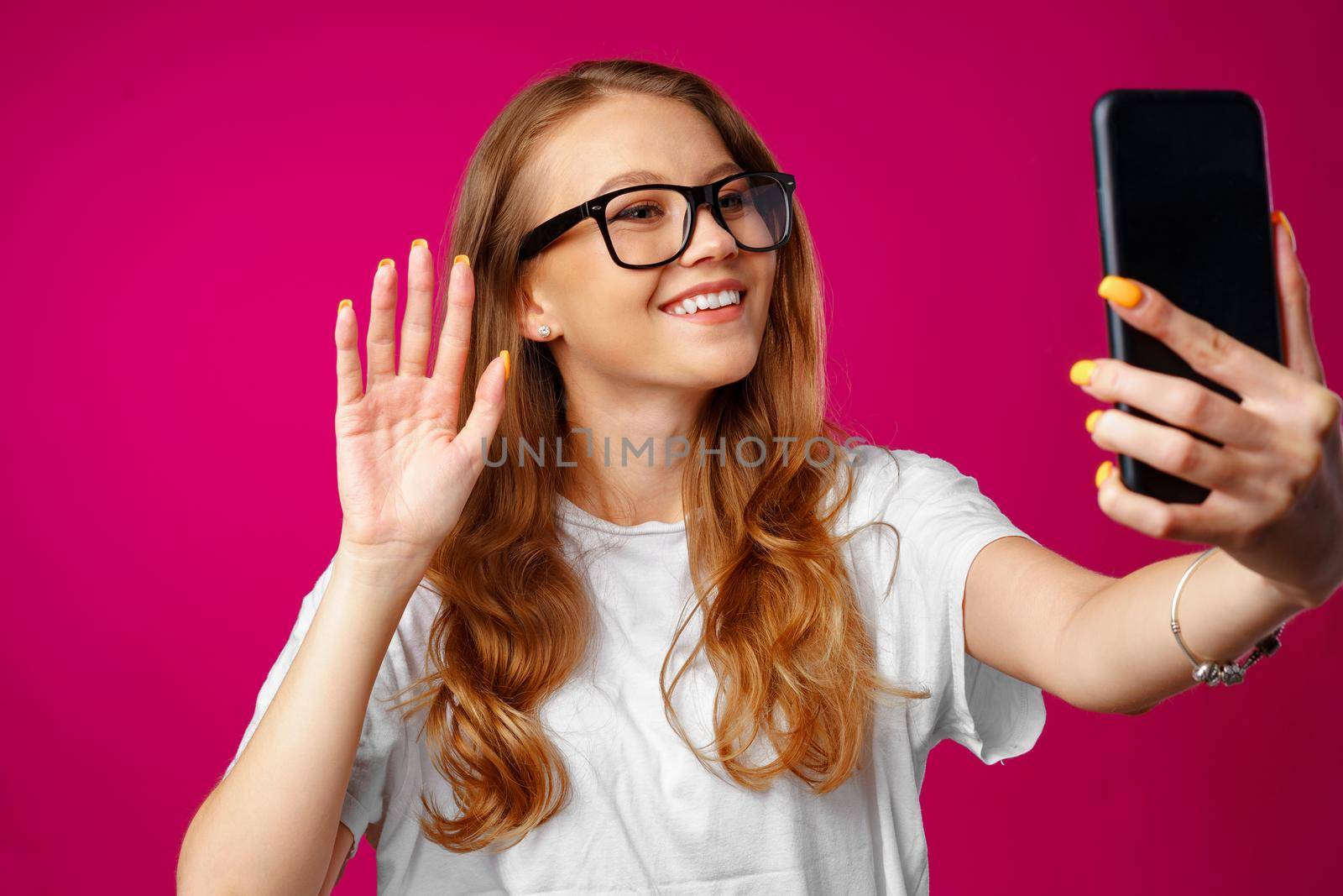 Happy casual young woman smiling and having a video call with her smartphone