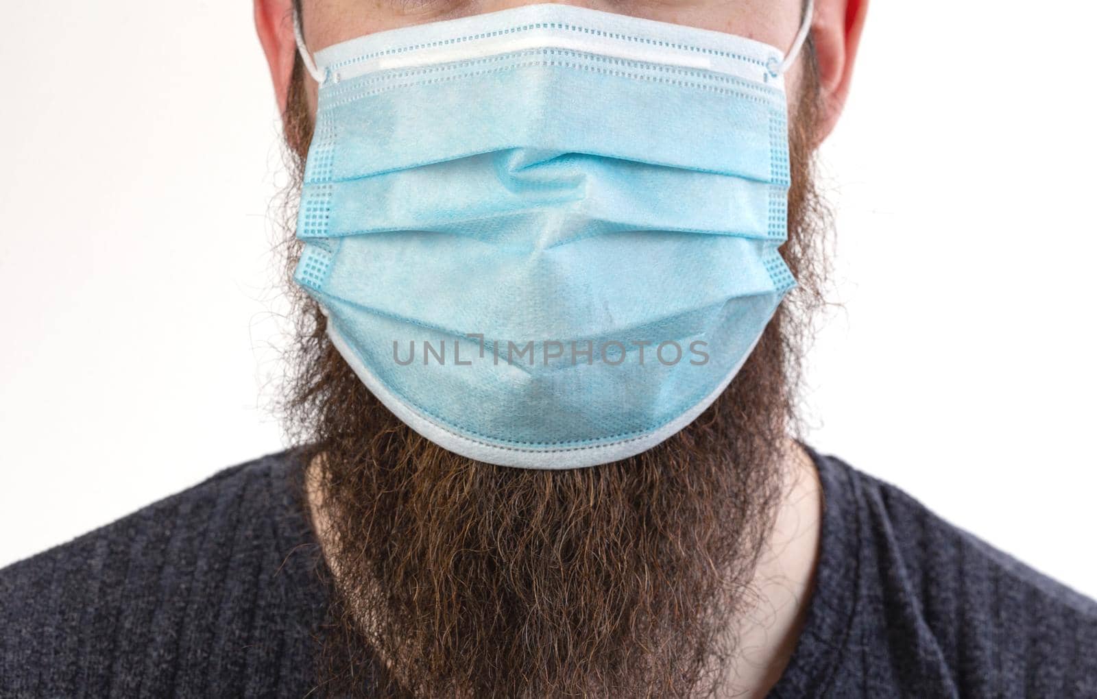 Caucasian young bearded adult man wearing a protective or surgical mask to avoid pollution and contagious virus and diseases isolated on white background, Covid-19, coronavirus,health,beard, epidemic concept close