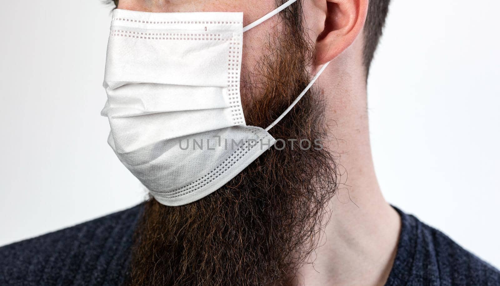 Caucasian young bearded adult man wearing a protective or surgical mask to avoid pollution and contagious virus and diseases isolated on white background, Covid-19, coronavirus,health,beard, epidemic concept close