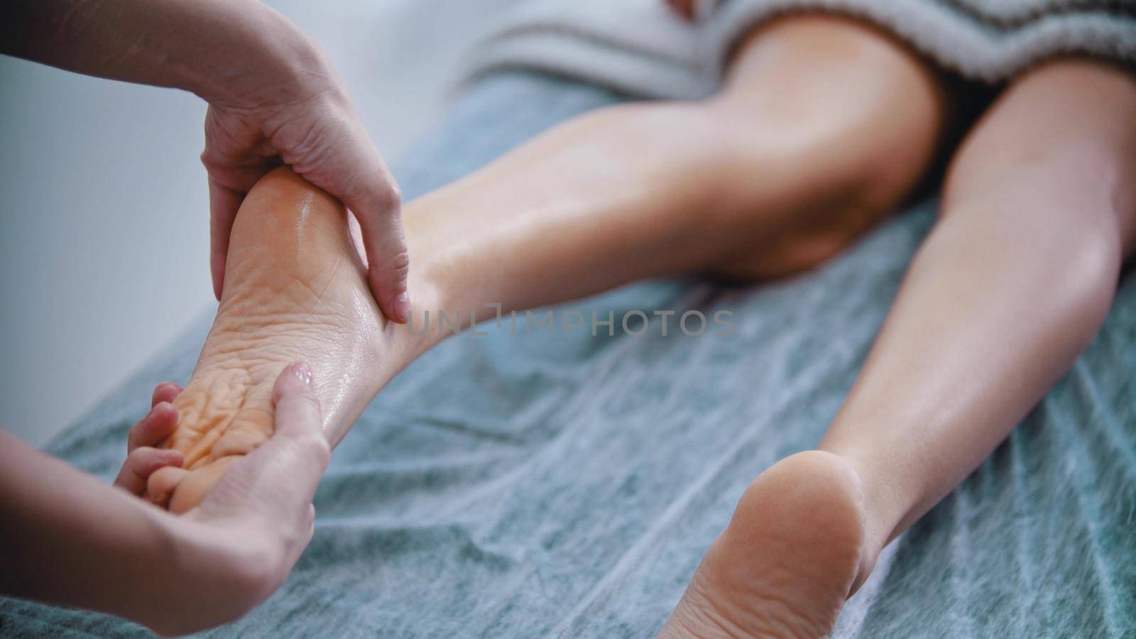 Massage - massage master is kneading womans feet with both hands - indoor