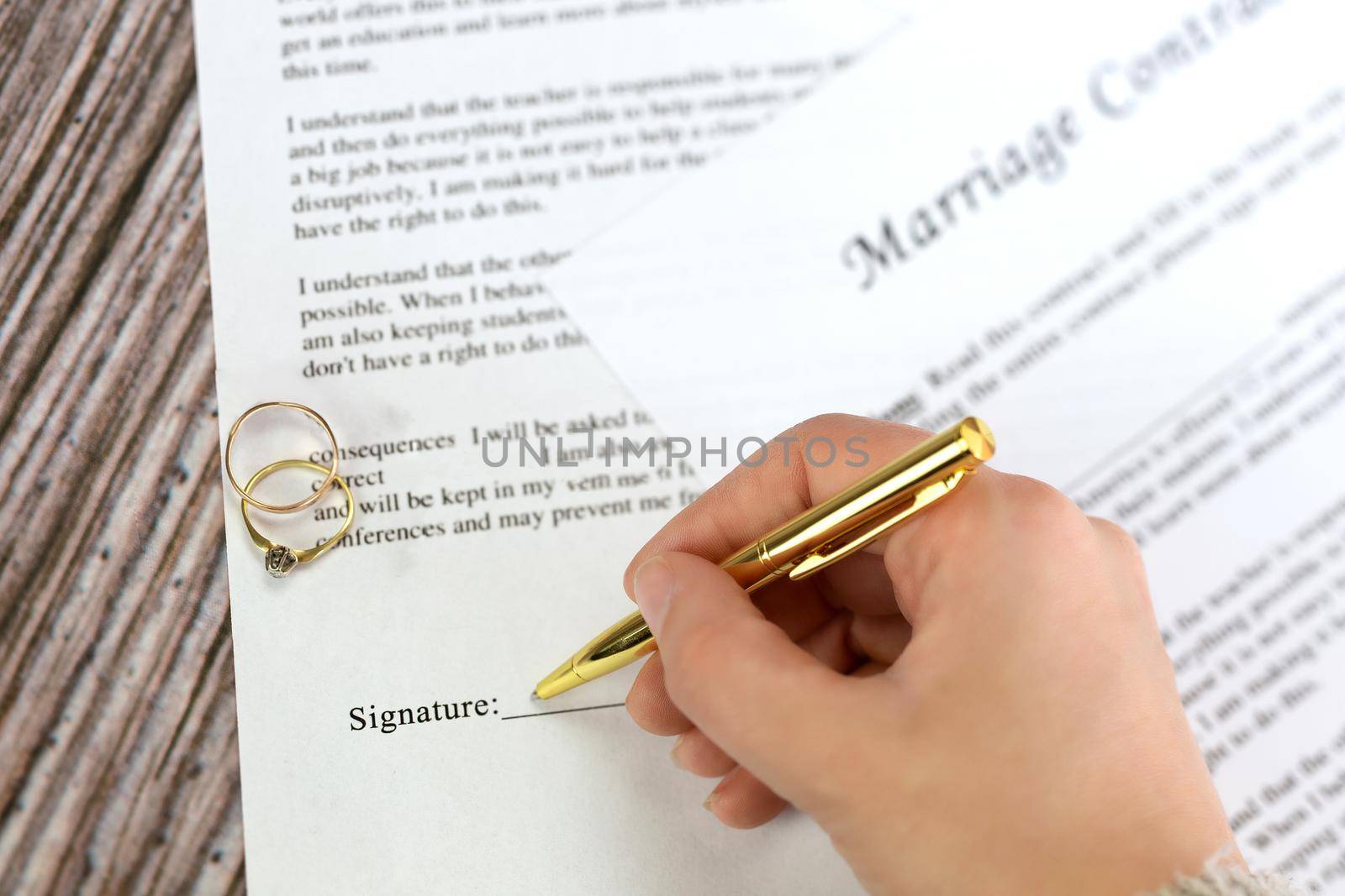 Marriage contract with two golden wedding rings and gold pen, prenuptial agreement, macro close up, sign with signanture,document,agreement concept romance