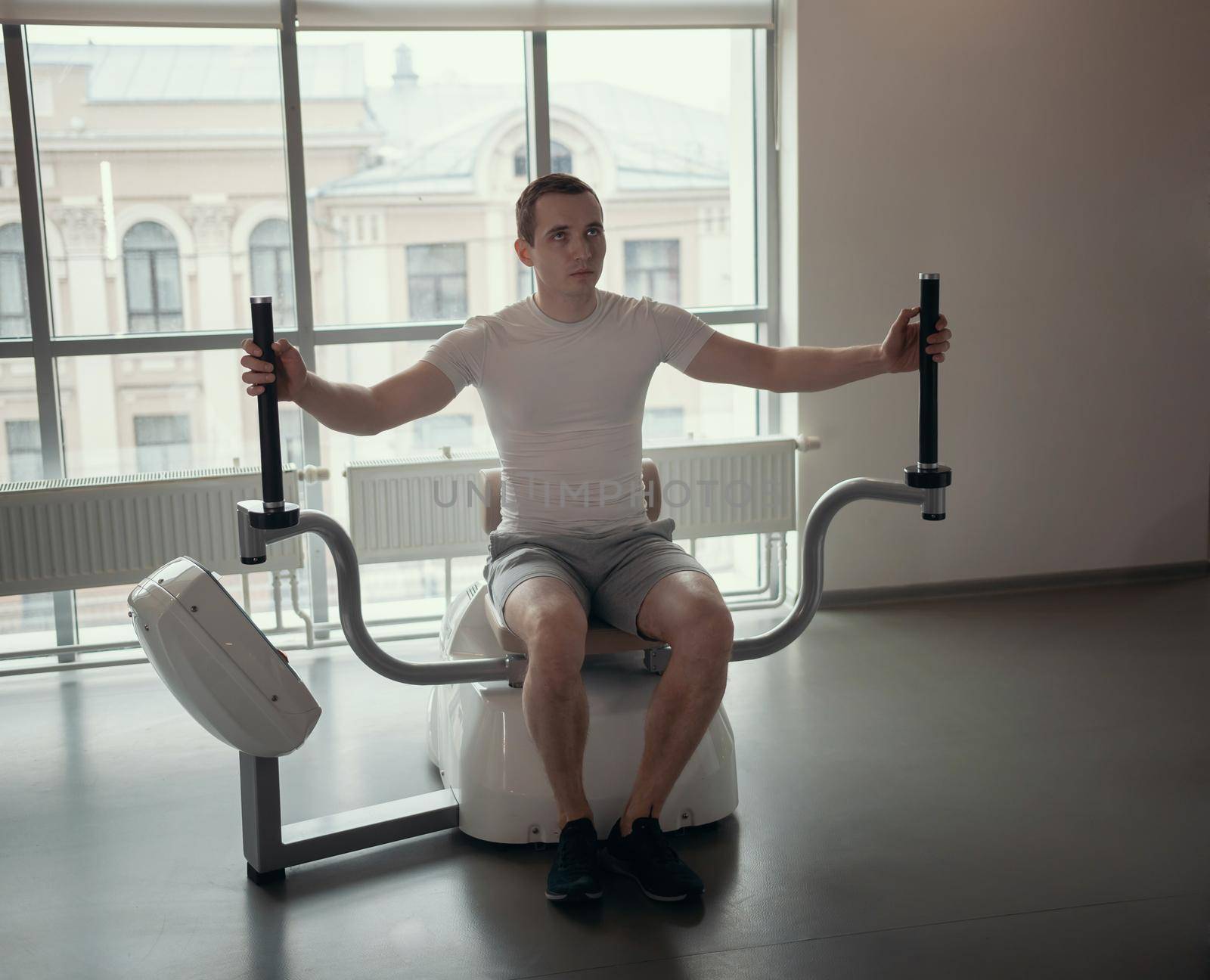 Modern gym - a guy sitting on the strength training machine. Mid shot