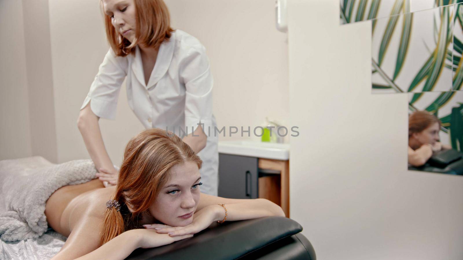 Young ginger woman with blue eyes having a massage treatment by Studia72