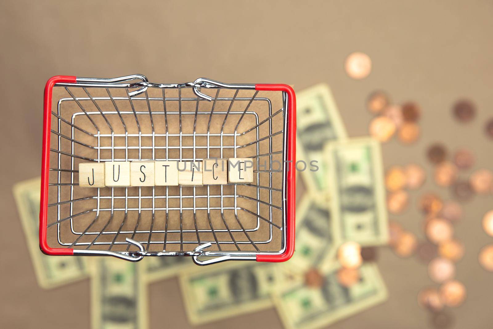 Justice written with wooden cubes in iron shopping basket with Money coins and bills on the background, Business,law,justice,Financial concept space for text by Annebel146