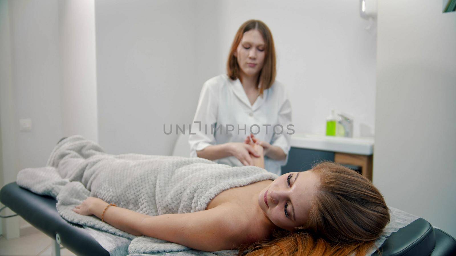 Female young massage therapist massaging hands of her woman client by Studia72