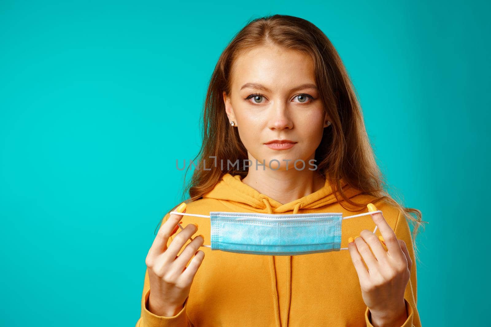 Young beautiful casual woman wearing protective medical mask against blue background