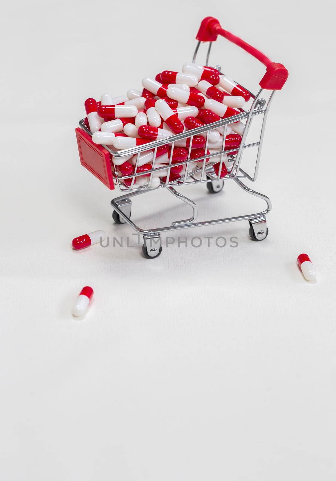 Shopping cart filled with medical capsules,pills,medication,drugs on white background top view with copy space, medicine,pharmacist and healthcare concept space for text
