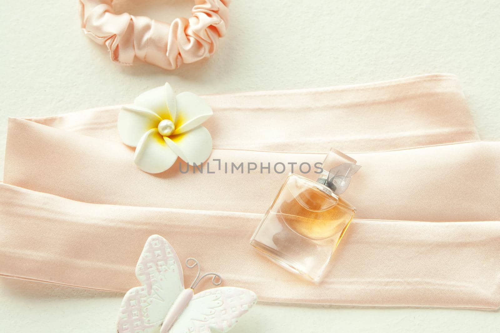 Pink women's perfume in beautiful bottle and white flower on pink background. silk pink rounded hairband isolated on white. Flat lay Hairdressing tools and accessories Hair Scrunchie, Hair Bands,