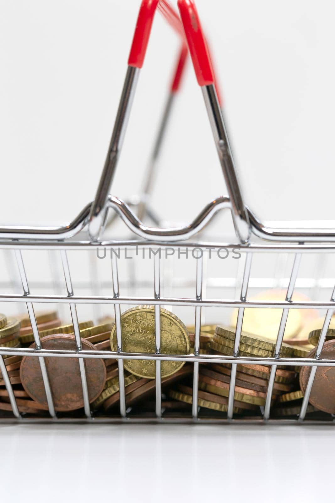 Iron shopping basket filled with euro coins isolated on white background, business and financial concept