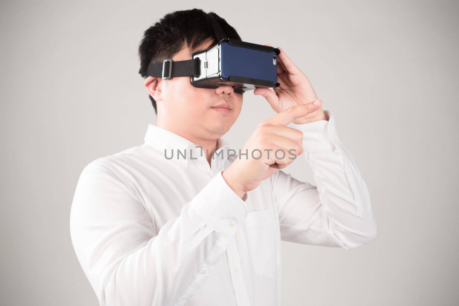 Man wearing virtual reality goggles watching movies or playing video games. He is isolated on a white background. The vr headset design is generic and no logos.