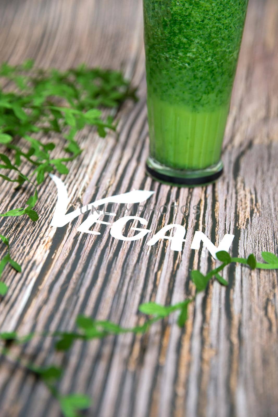 Healthy fresh green shake or smoothie with green vegetables spinach, avocado, apple on wooden background texture with the text Vegan top view, copy space freshness