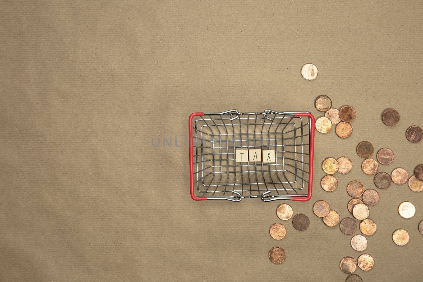 Tax written with wooden cubes top view in shopping basket with money coins and bills on the background. Business and financial concept Copy space