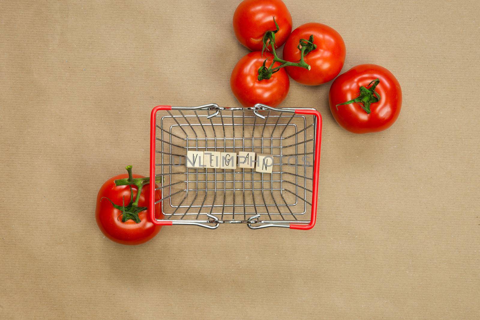 Vegan written on wooden cubes surrounded with vegetables in shoppin basket top view with craft paper background, Vegan, Healthy food, Vegetarian concept, copy space lifestyle