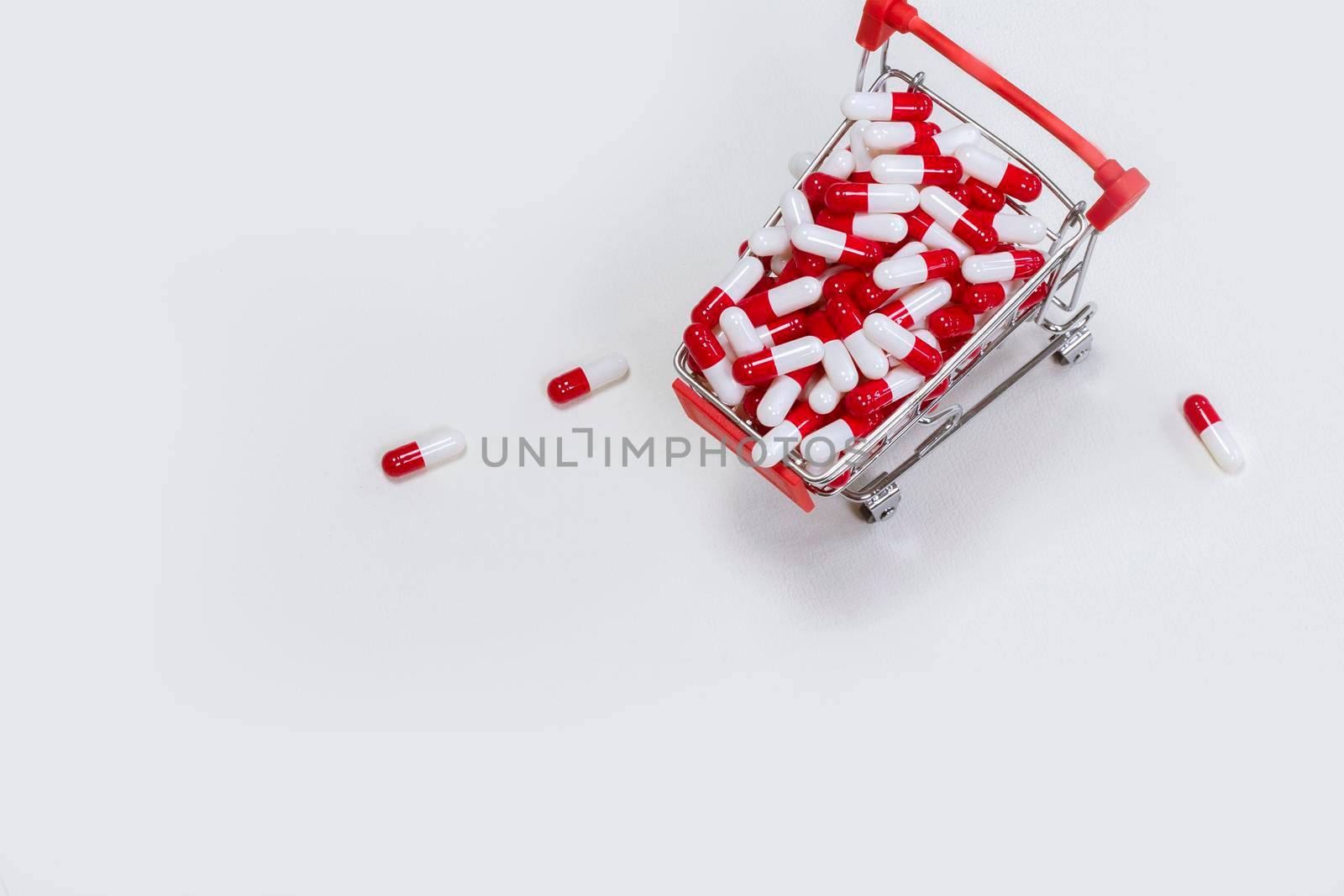 Shopping cart filled with medical capsules,pills,medication,drugs on white background top view with copy space, medicine,pharmacist and healthcare concept space for text