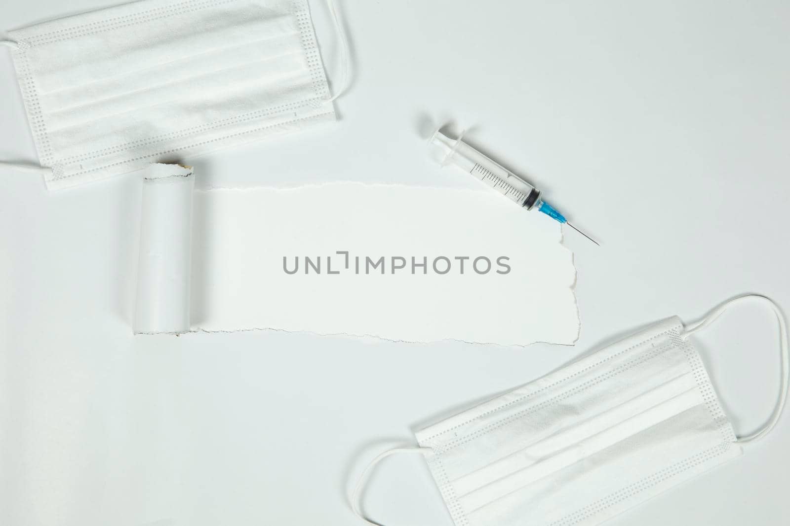 the sheet of torn paper against the white background with syringe and protective white medical mask for virus, Vaccination,health,covid-19 concept. top view, copy space space for text