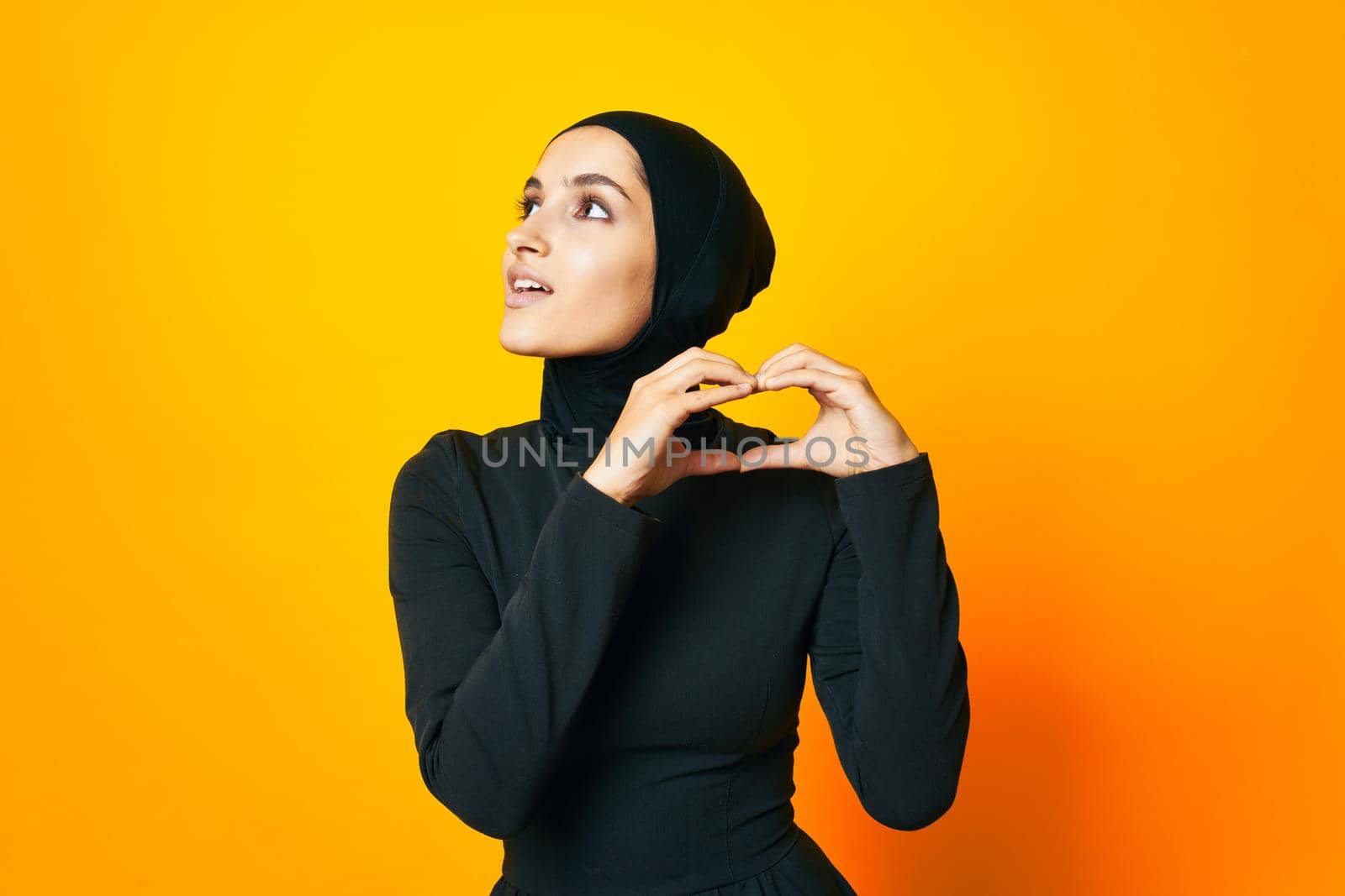 pretty woman in black hijab posing fashion hand gesture yellow background. High quality photo