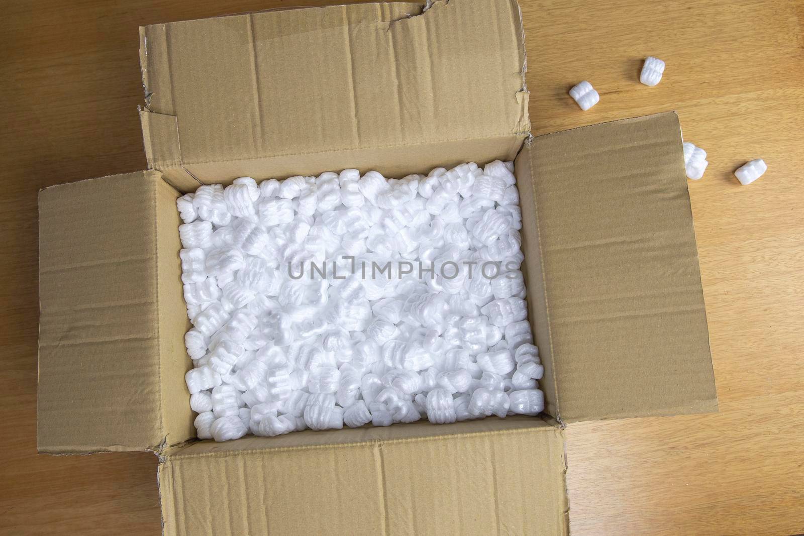 A cardboard box with packing foam top view, Delivery box for fragile product on wooden table copy space