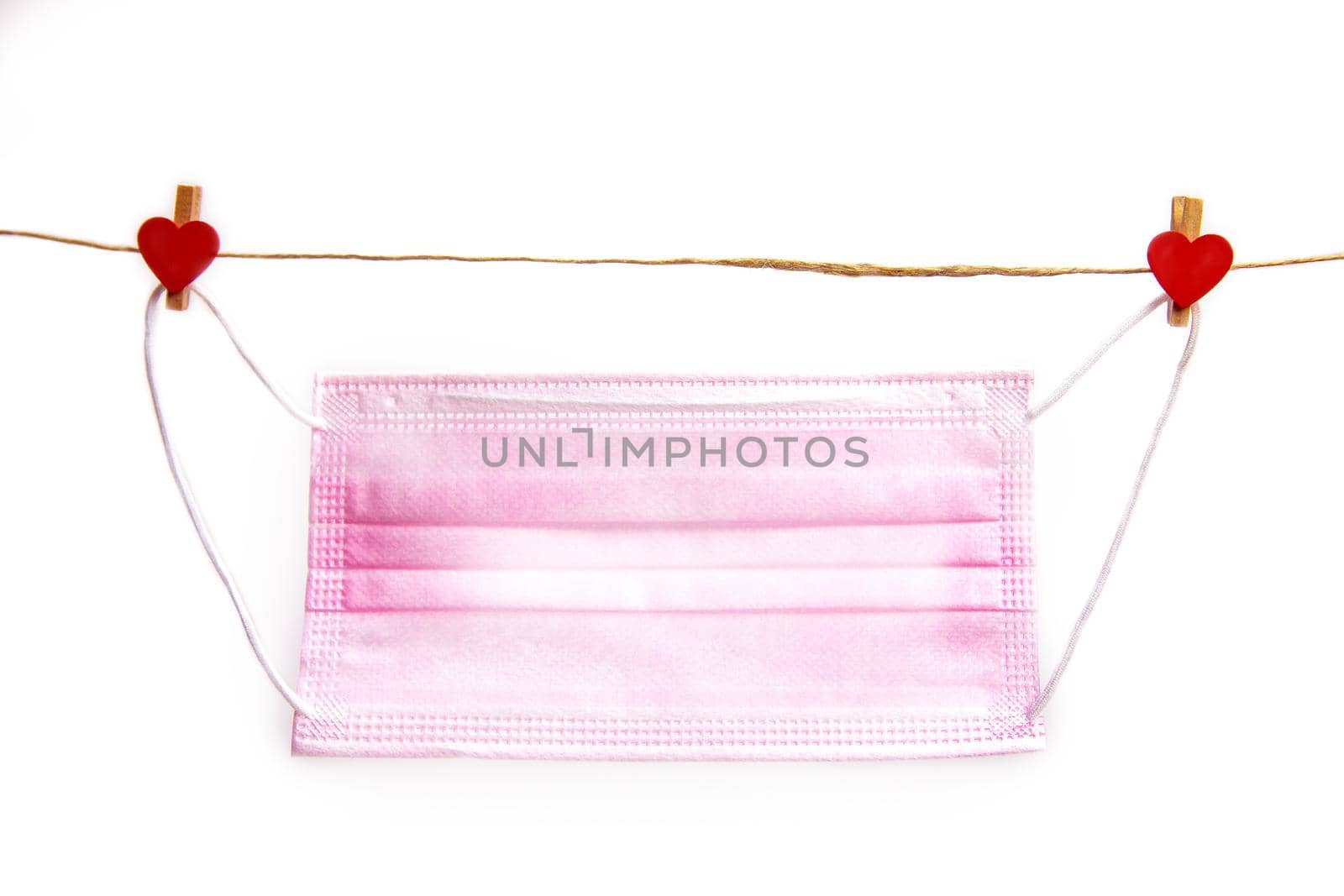 Pink protective medical mask hanging with clothes pegs in heart shape isolated on white background, Health, Covid-19 or Valentine's Day concept background love