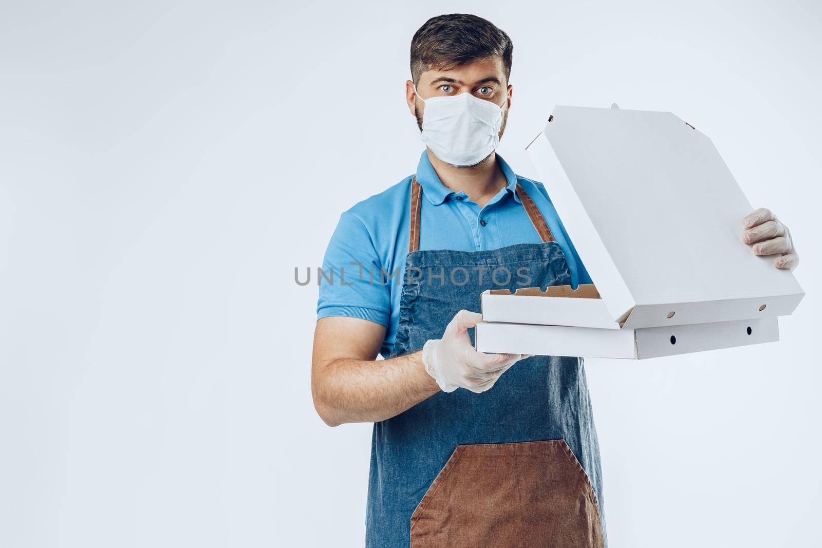 Pizza delivery man in medical gloves and mask against grey background. Safe service while coronavirus covid-19 outbreak