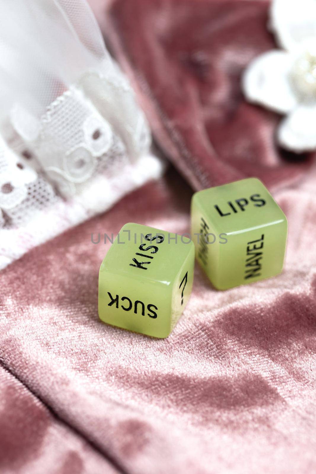 Two dice for erotic sexual game with the text kiss lips and neck on pink satin fabric background, Valentines Day, Love, Sex concept playful game couples