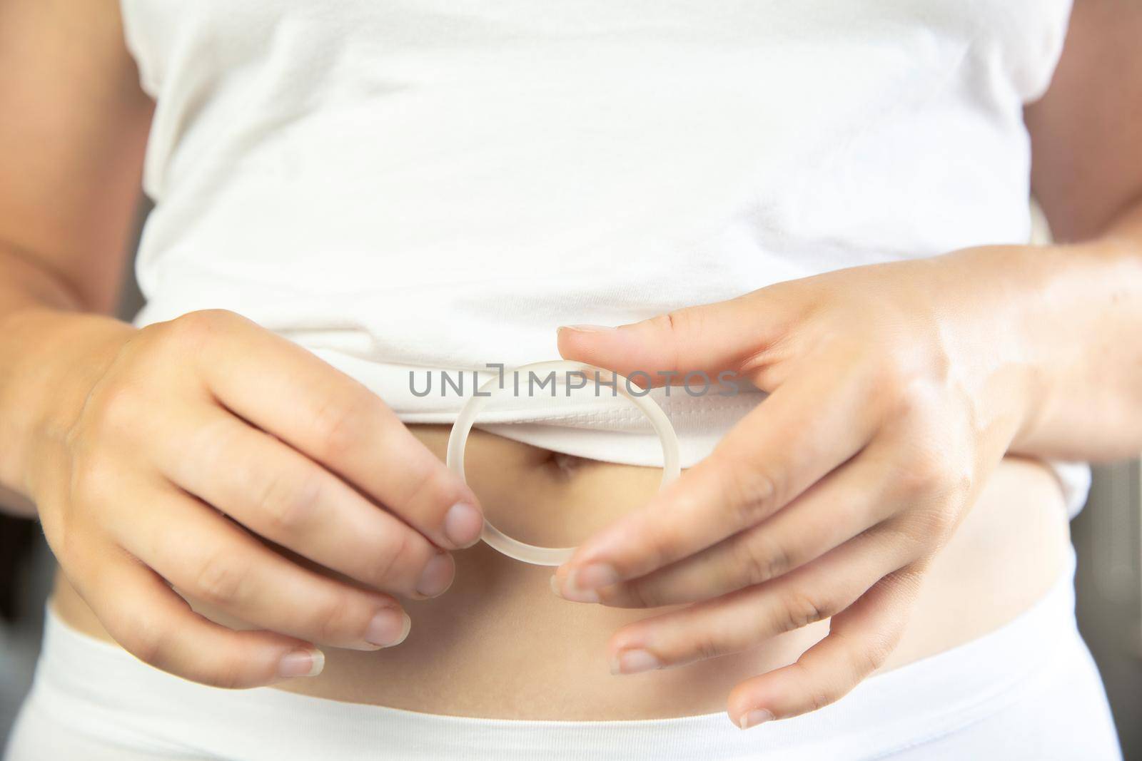 Birth control ,hormone, contraception ring in a womans hand white underwear and belly, vaginal ring for contraceptive use with copy space closeup