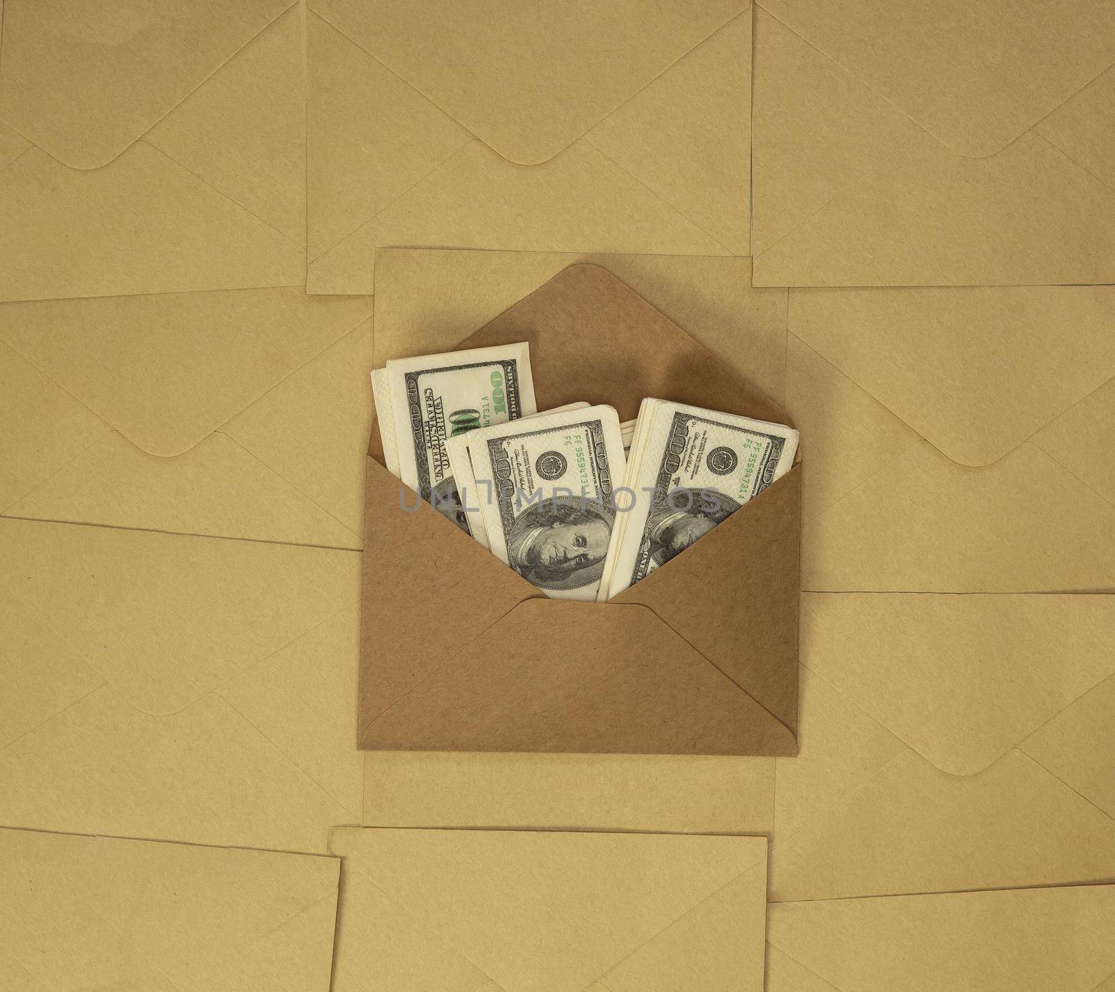 Craft paper envelope with one hundred dollar bills on brown plain background top view, copy space, business and financial concept background space for text