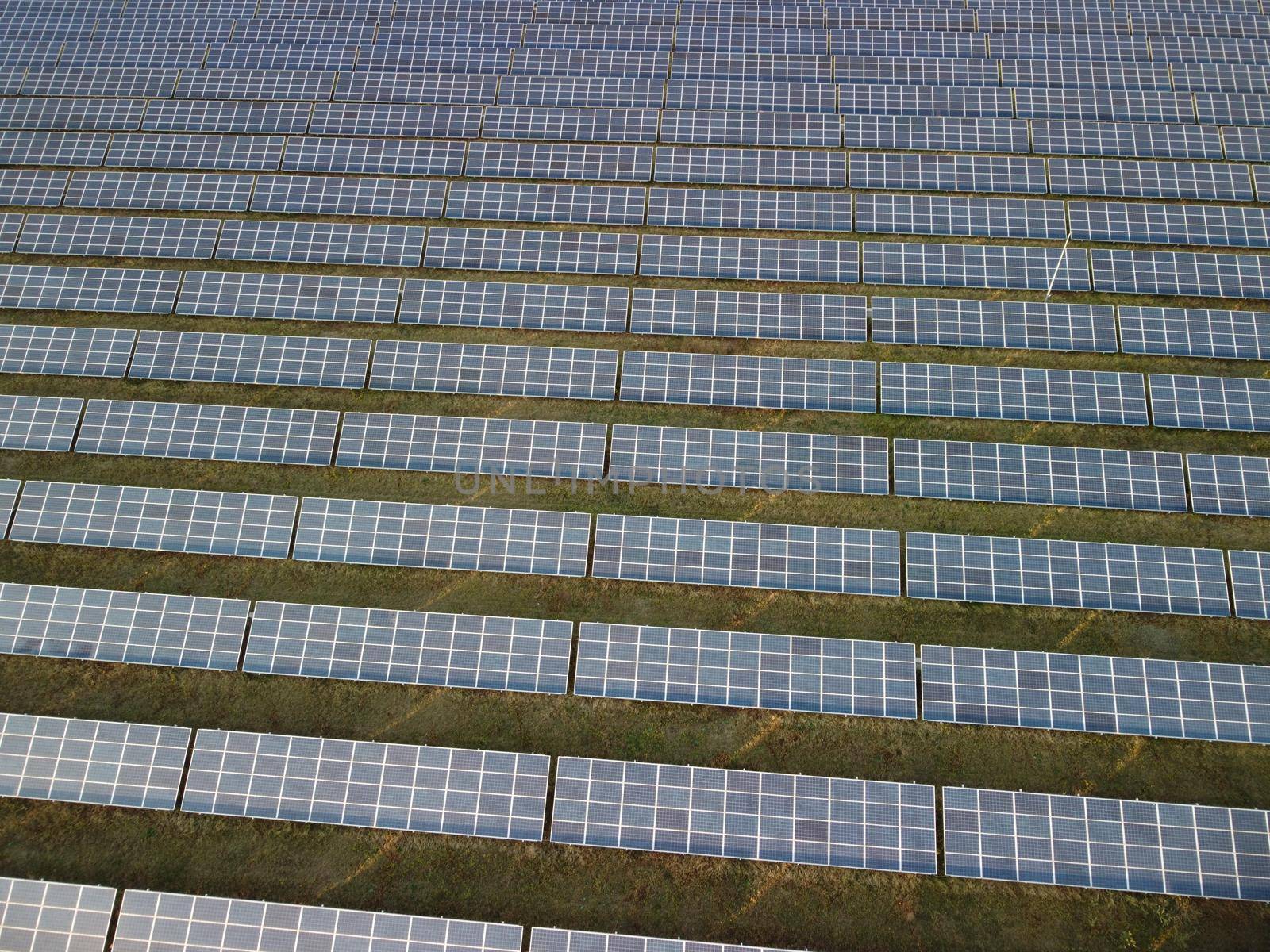 Aerial top view of a solar panels power plant. Photovoltaic solar panels at sunrise and sunset in countryside from above. Modern technology, climate care, earth saving, renewable energy concept