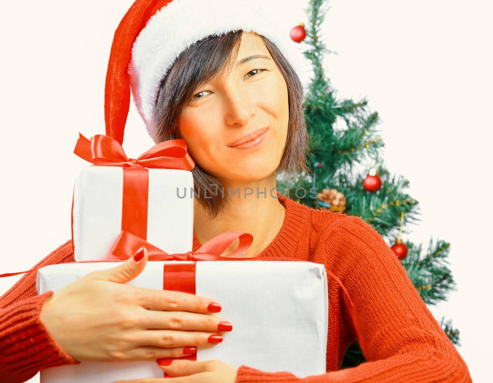 Young woman in santa hat is smiling and hugging gift box