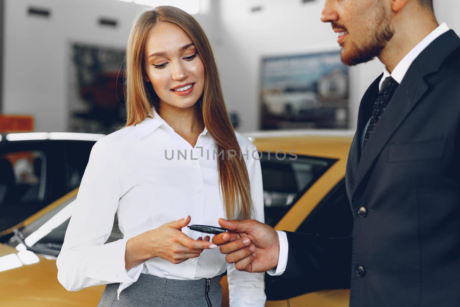 Young attractive woman buying a new car in car salon close up