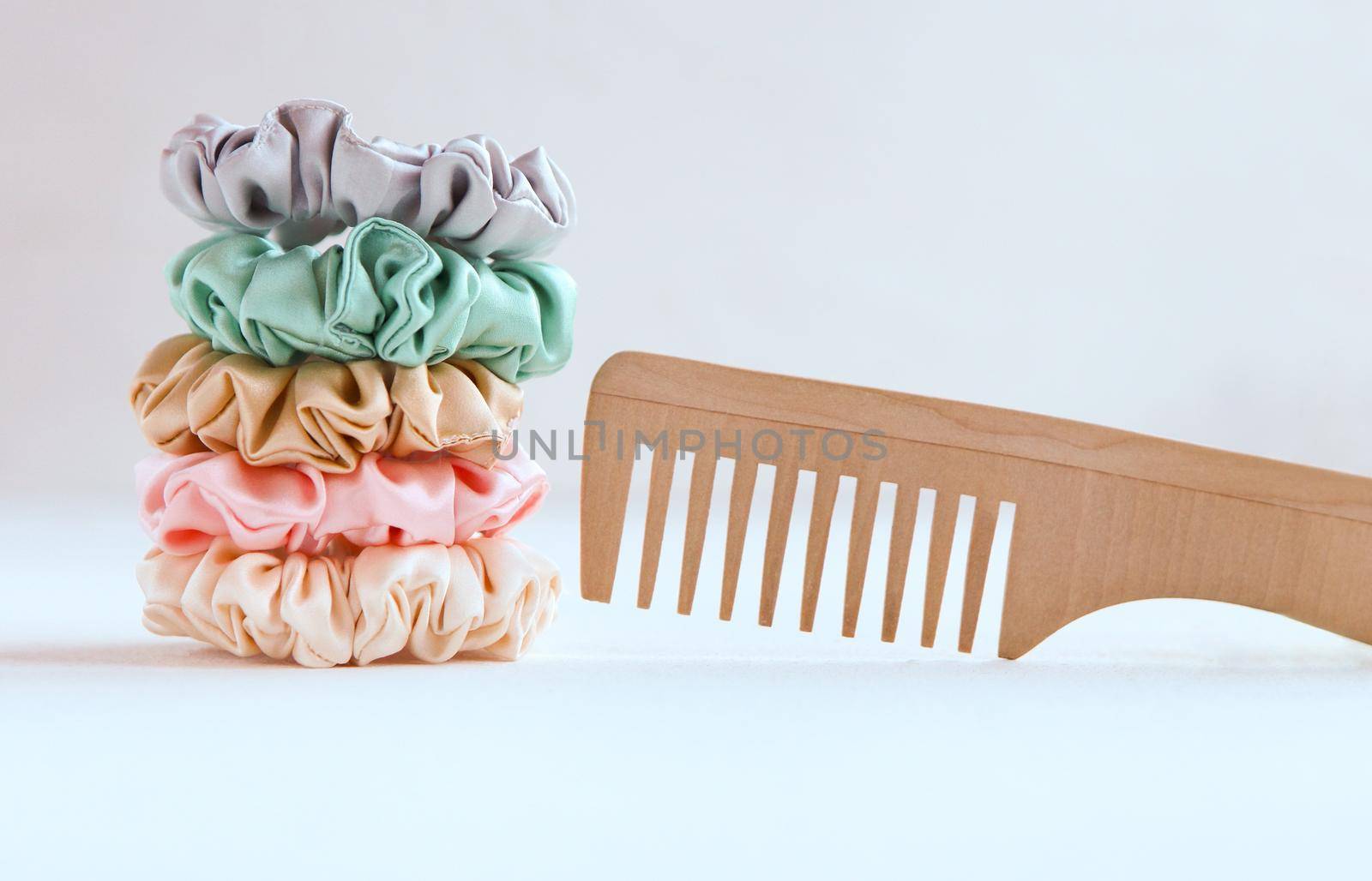 Wooden hairbrush and Lot of Colorful silk Scrunchies isolated on white. Luxury Hairdressing tools and accessories. Hair Scrunchies, Elastic HairBands, Bobble Sports Scrunchie Hairband