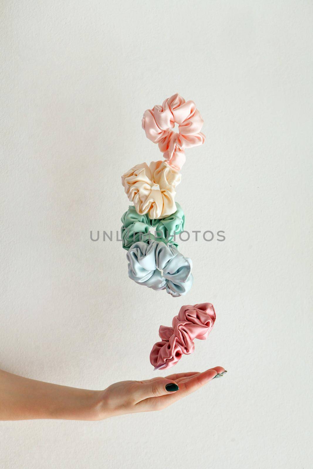 Lot of floating Colorful silk Scrunchies on womas hand isolated white. Hairdressing tools and accessories. Hair Scrunchies, Elastic HairBands, flying or falling Scrunchie Hairband for girls or ladies