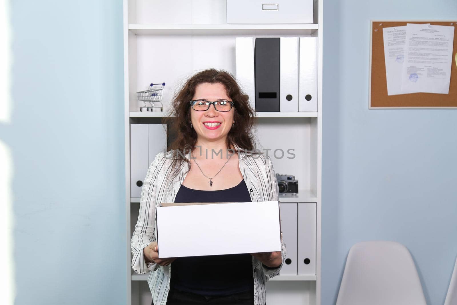 Concept of dismissal from work. Happy woman with carton box with her stationery stuff, girl was fired from her job