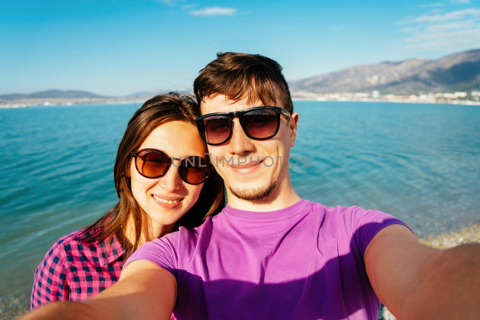 Happy young couple in love taking self-portrait on beach on background of blue sea