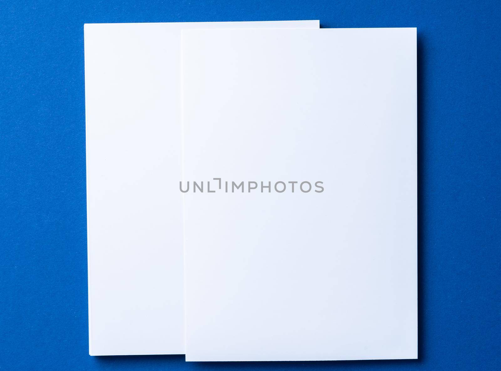Blank paper business mock up on classic blue background, top view