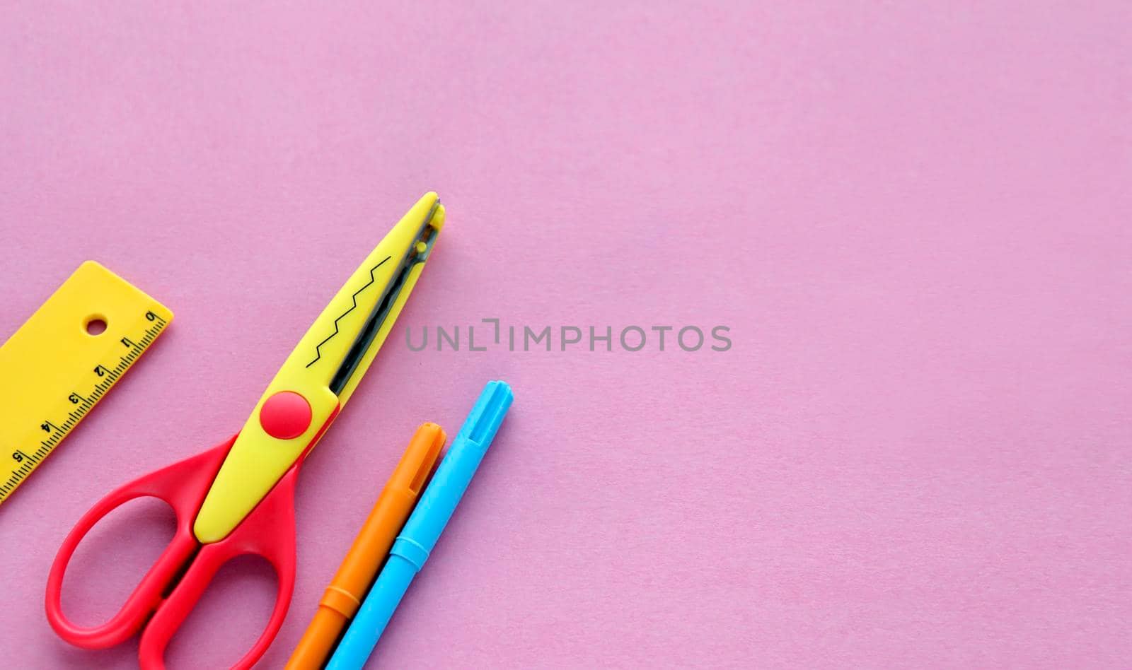 scissors, ruler and crayons on a pink background. Creative, fashionable, minimalistic, school or office workspace with supplies on cyan background. Flat lay.