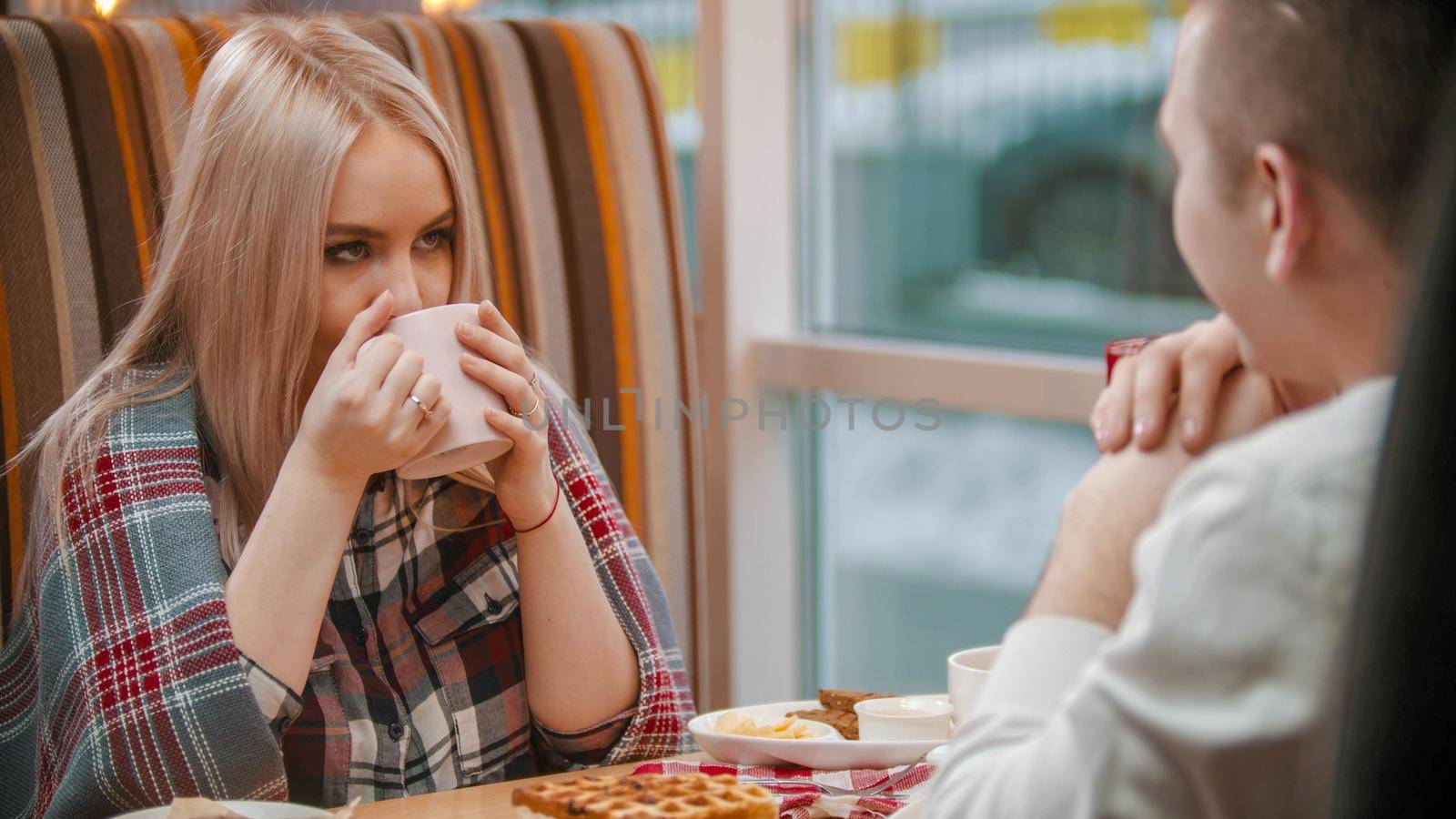 A young woman drinks coffee on the date. Mid shot